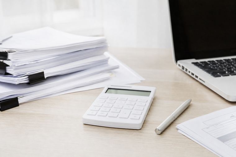 Ufficio essenziale con due schermi accesi, dove si calcolano i costi della segreteria.